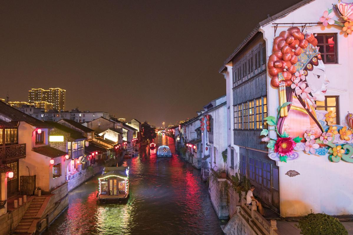 The quaint buildings along the waterway and charming bridges over the ancient canal in Wuxi feature beautiful illuminations in the evening. [Photo/VCG]