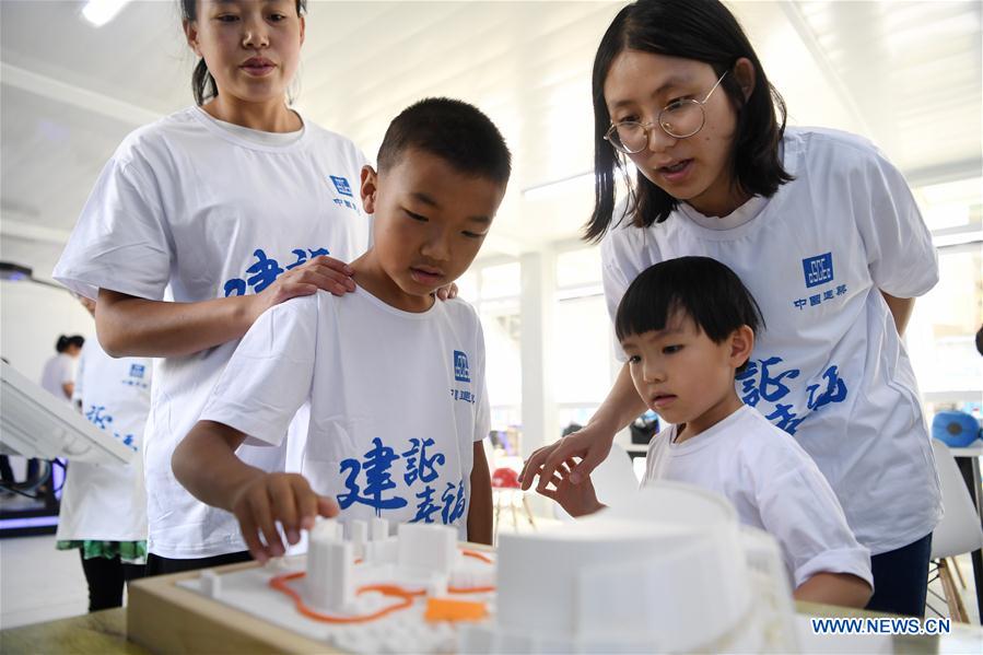 Parents and children look at 3D printing models during a caring activity in Anning District of Lanzhou, northwest China