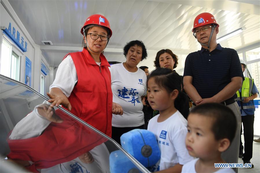 A volunteer introduces the construction situation during a caring activity in Anning District of Lanzhou, northwest China