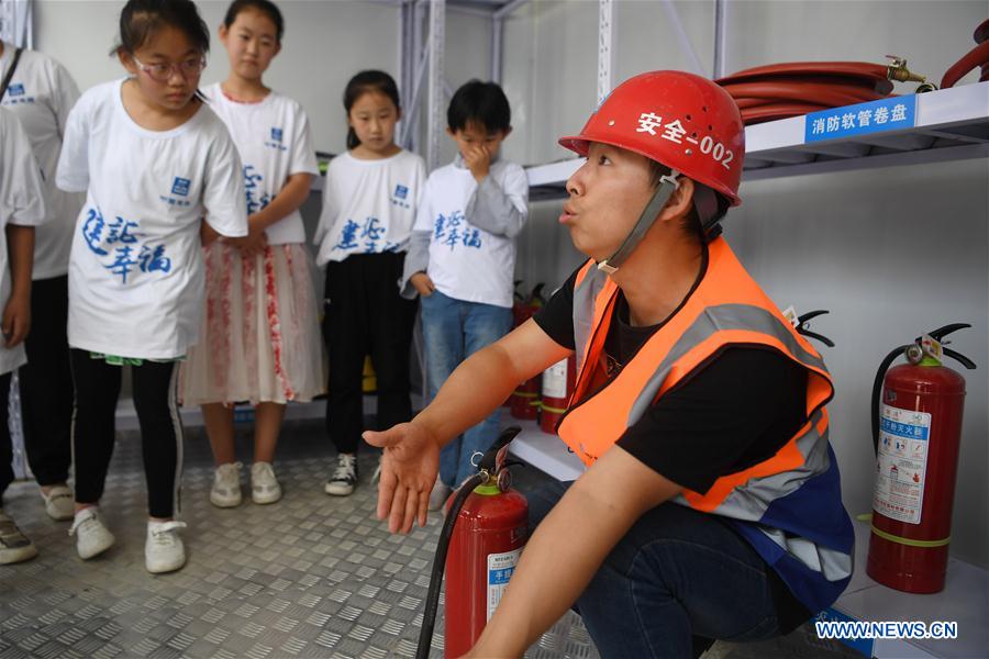 A staff member of the China Construction Third Engineering Bureau Co., Ltd. introduces safety knowledge to children during a caring activity in Anning District of Lanzhou, northwest China