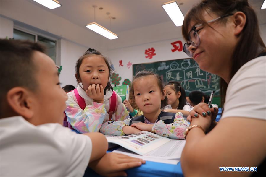 A teacher talks with pupils at a primary school in Longnan City, northwest China