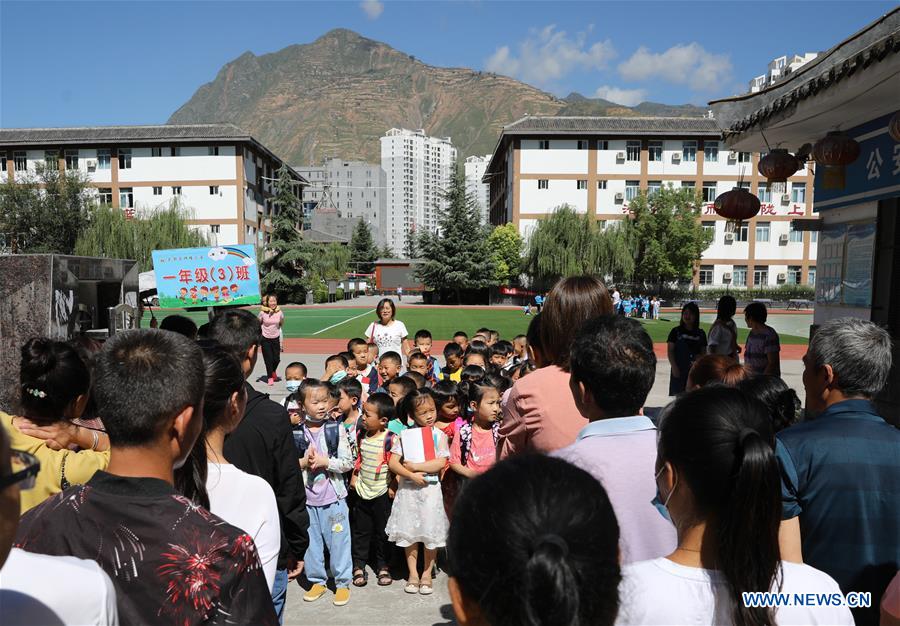 Parents wait for pupils after school at a primary school in Longnan City, northwest China