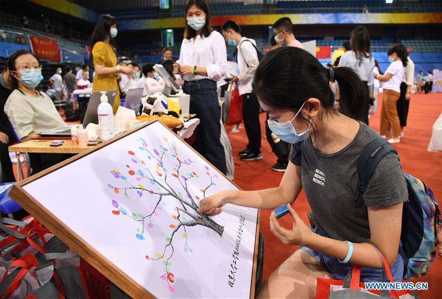 A freshman (front) presses her finger onto a painting while registering at the Khoo Teck Puat Gymnasium of the Peking University in Beijing, capital of China on Sept. 1, 2020. As the new school year starts, college students are returning to campus in Beijing under tight epidemic prevention and control measures. (Xinhua/Ren Chao)