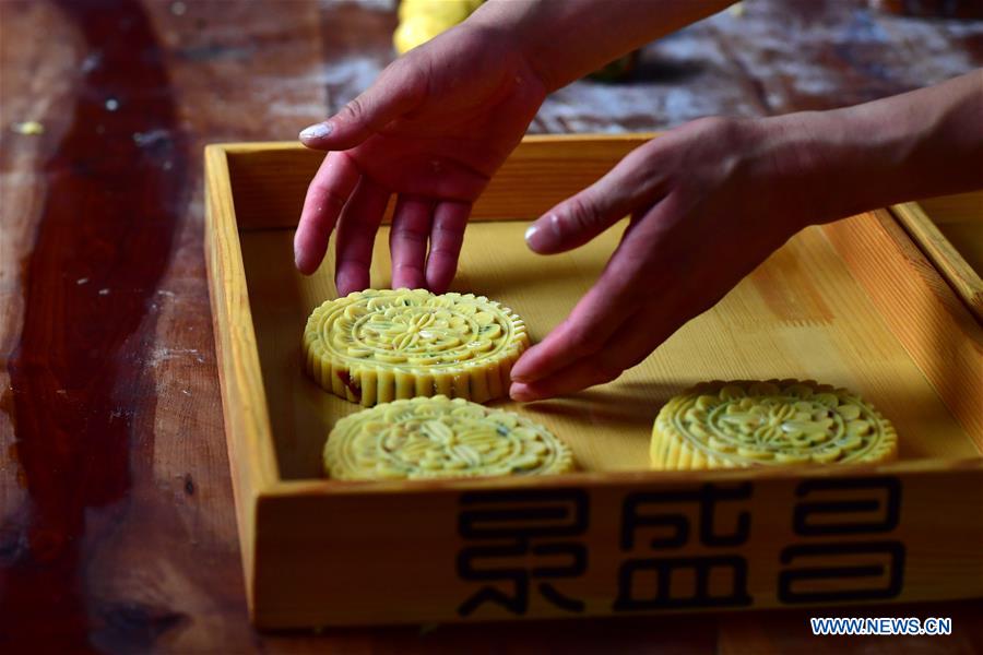Zhang Xu puts away mooncakes ready for baking at the mooncake bakery Jingshengchang in Xiayi County, Shangqiu, central China