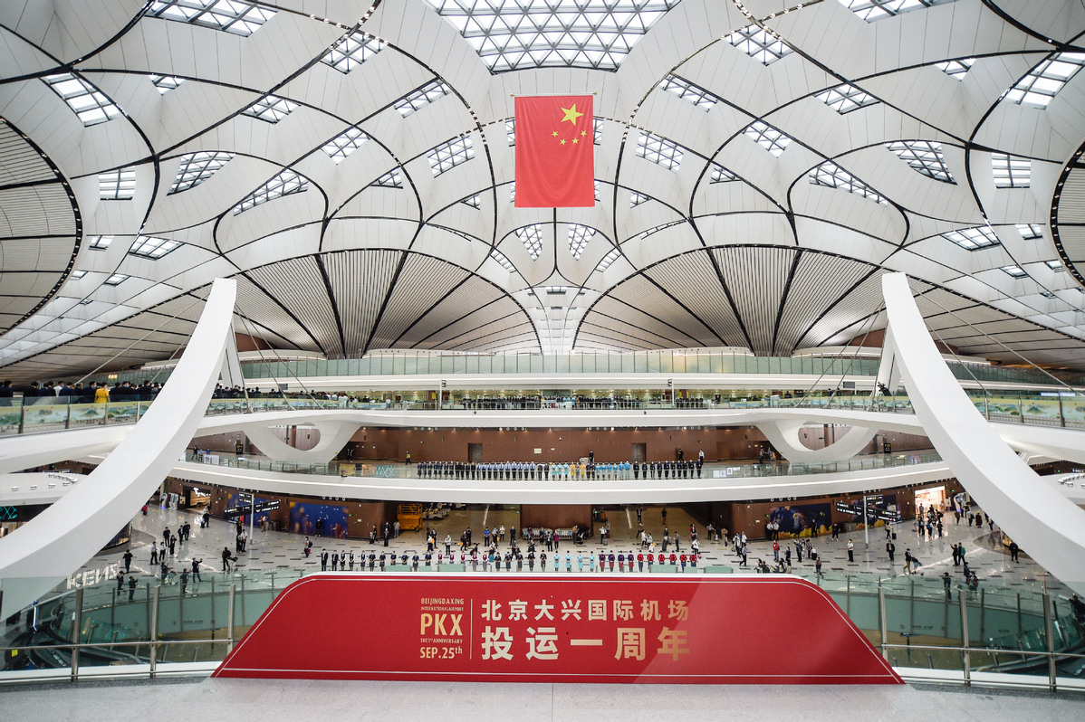 A flag-raising ceremony is held by the Civil Aviation Administration of China to mark the first anniversary of the Beijing Daxing International Airport in Beijing, capital of China, on Sept 25, 2020. The Beijing Daxing International Airport celebrated its first anniversary on Friday. [Photo/Xinhua]The new Beijing Daxing International Airport, which is weathering the tough blow brought on by the COVID-19 pandemic earlier this year, marked its first anniversary on Friday with total annual passenger throughput exceeding 10 million."Daxing airport has handled some 84,000 takeoffs and landings since it began operating on Sept 25 last year, along with 10.23 million passenger trips and 40,000 metric tons of cargo," Yao Yabo, general manager of Beijing Daxing International Airport, said at a news conference.At its busiest, the airport handled over 660 flights a day in September, with daily passenger flow peaking at 92,000, he added.The figure comes as domestic air travel in China is seeing a vibrant recovery amid effective epidemic control. Over 45.3 million domestic passenger trips were made last month, recovering to more than 80 percent of the level during the same period last year, according to the Civil Aviation Administration of China.The robust growth in passenger volume of Daxing airport is also facilitated by multiplying flights, from about 200 flights per day during initial operations to about 650 daily flights currently, as airlines have been transferring flight operations from Beijing Capital International Airport, he said.Han Wensheng, deputy Party secretary of China Southern Airlines, said the company has so far transferred 80 percent of its flights in Beijing to Daxing airport and is expected to move all of its flights by the end of next month.