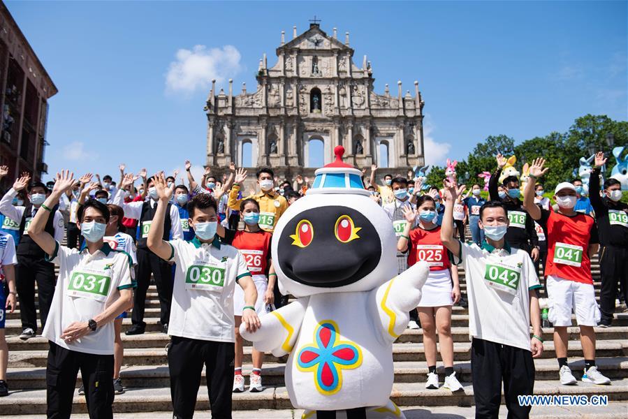 Participants of a tray race and the mascot of Macao tourism pose for photos in front of the Ruins of St. Paul
