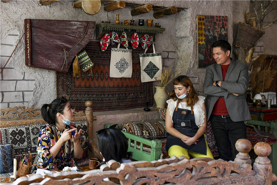 Mardan Ablimit (right) and his wife, Dilnar Akbar, chat with a customer at Kashgar Corner, their coffee shop in the Old Town, on Sept 15. MA KAI/XINHUAIn 2010, the central government started a 7 billion yuan ($1 billion), four-year renovation project to render the buildings earthquake-proof while maintaining their traditional Uygur charm.Nearly 50,000 families had their dilapidated old houses renovated under the project. Modern infrastructure and amenities have made people