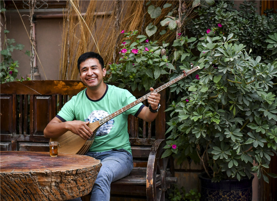 A man plays the dutar and sings outside a building in the Old Town. MA KAI/XINHUABlend of culturesMewlan Turaq, 27, owns a clothing boutique in the Old Town. He designs and displays over a dozen pieces of Uygur clothing in the shop, illustrating the changes in the traditional clothing during the past century.The clothing is very popular with tourists, along with other products such as vintage accessories, bags and even mobile phone cases decorated with Uygur patterns.Many travelers enjoy renting the clothes and paying photographers to take pictures of them in the Old Town.