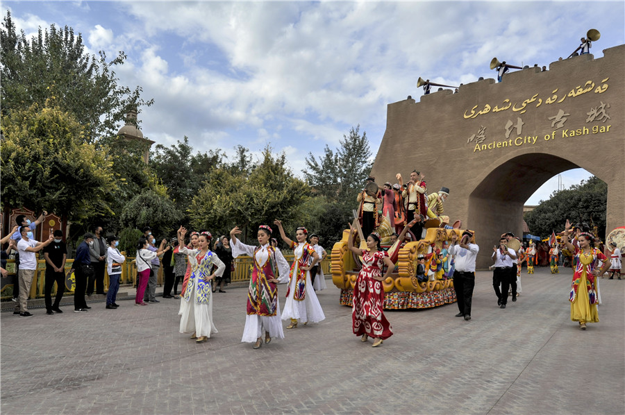 Tourists watch a dance performance in the Old Town in Kashgar, Xinjiang Uygur autonomous region. MA KAI/XINHUA"We can see that time has left different marks on our clothes, and different cultures have blended. The cultures of East and West have met and melded in Kashgar, an important trading post on the ancient Silk Road, and that shows in the evolution of local fashion," Mewlan said.He said his inspiration comes from the Old Town itself. When he wanders down the winding alleyways the shape of a window, the patterns on a carpet or the intricate carving on a wooden ornament can be his muse.