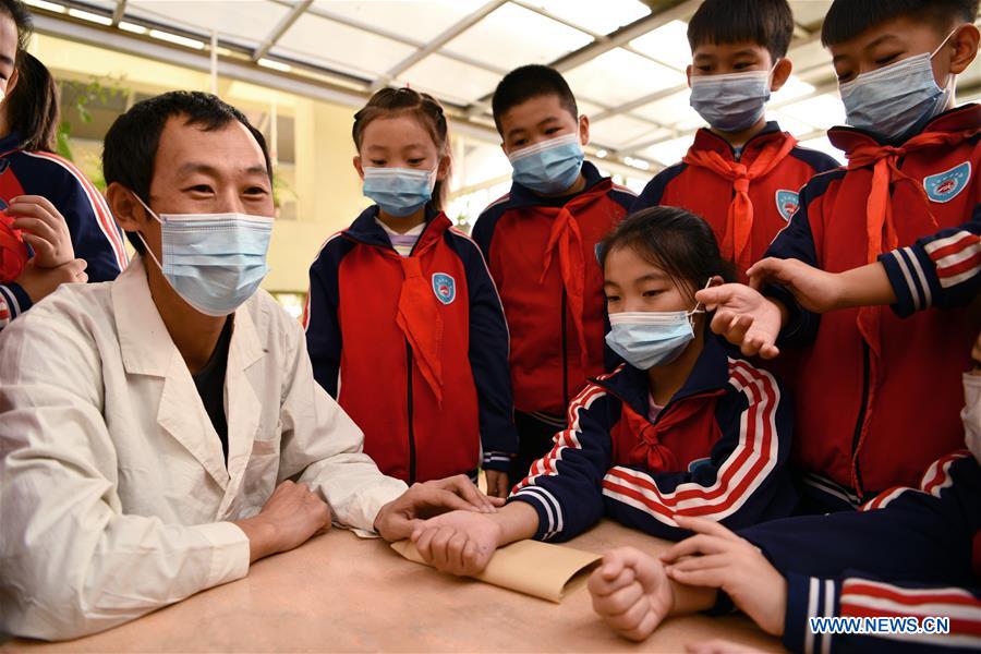 A doctor feels the pulse of a pupil during a lesson on traditional Chinese medicine (TCM) at a primary school in Shijiazhuang, north China