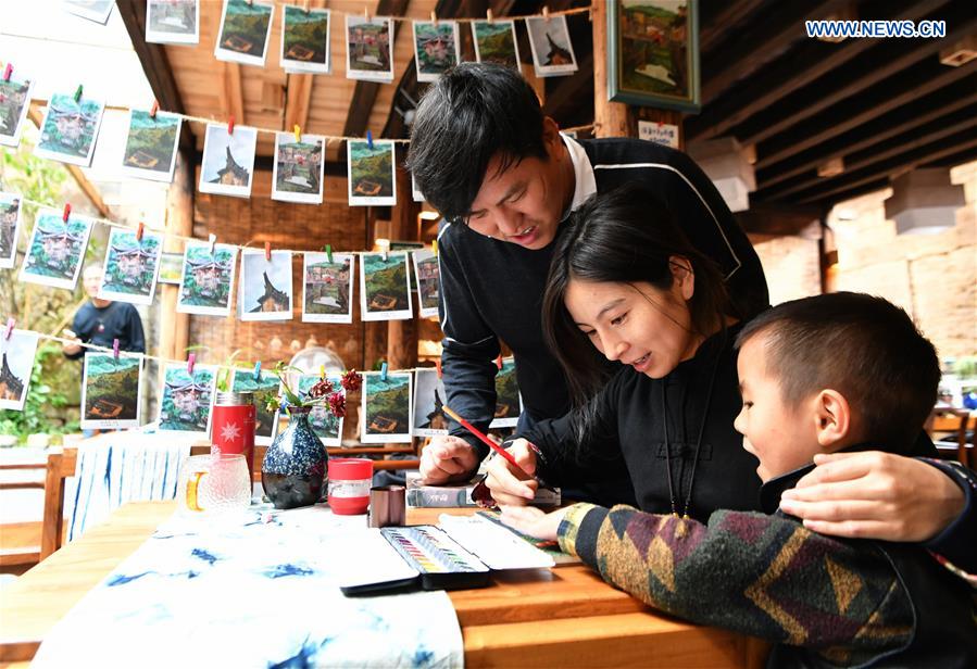 Hu Wenliang (1st L), a professional designer introduced to Longtan Village who started a cultural and creative space here, makes post cards with his family in Longtan Village of Pingnan County in Ningde City, southeast China
