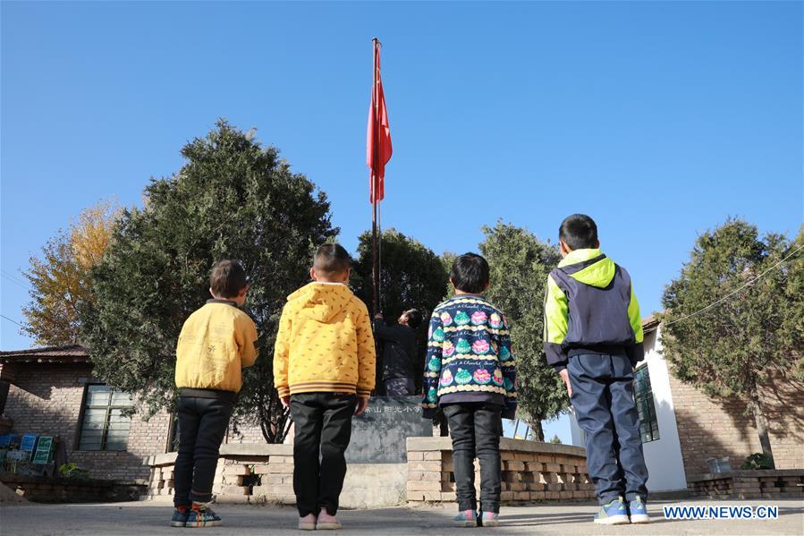 Wang Jianlin raises the national flag with students in Changshan School, Huining County, northwest China