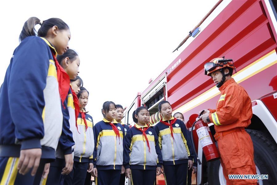 A firefighter demonstrates the use of fire-fighting equipment to students at a school in Xingtai City, north China