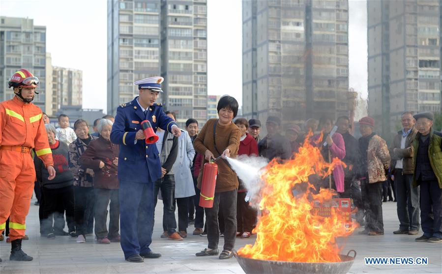 A resident learns to use fire extinguisher under the instruction of a firefighter in Peng