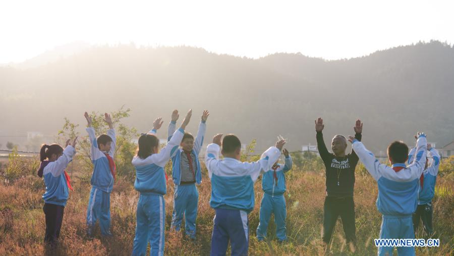 Photo taken on Nov. 10, 2020 shows Zhu Zhihui (3rd R) and student of Matian School warming up before a training session in Pingxiang, east China