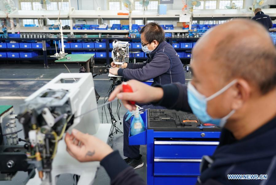 An engineer installs a smart sewing machine in a workshop in the Lintong Production Base of the China Typical Industries Group Co., Ltd., a state-owned enterprise, in Xi
