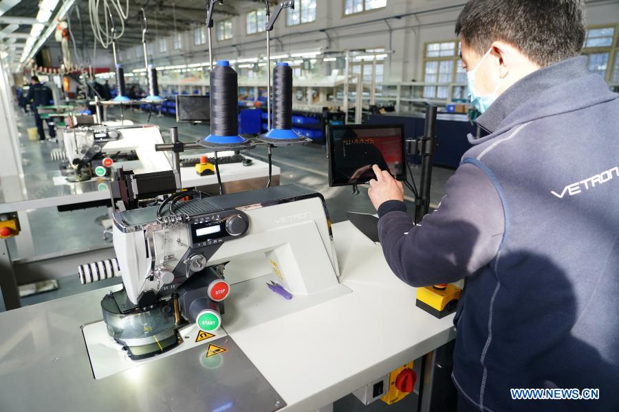 An engineer adjusts an automatic sewing machine in a workshop in the Lintong Production Base of the China Typical Industries Group Co., Ltd., a state-owned enterprise, in Xi