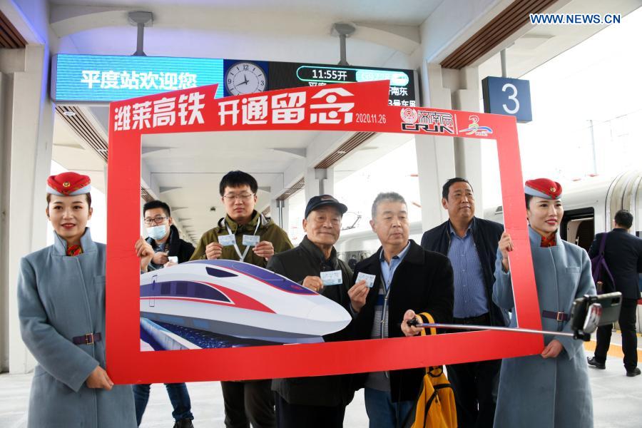 Passengers of the train No. G9228 pose for photos during the inauguration of the Weifang-Laixi high-speed railway at the Pingdu Railway Station in Pingdu City, east China