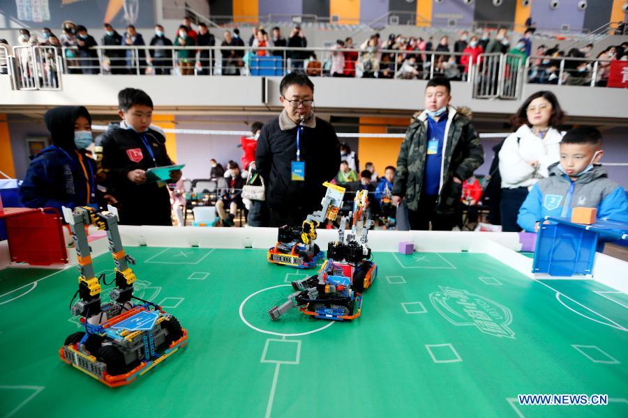 Contestants participate in a robot soccer match during a robotics competition for middle and primary school students in Jimo District of Qingdao, east China