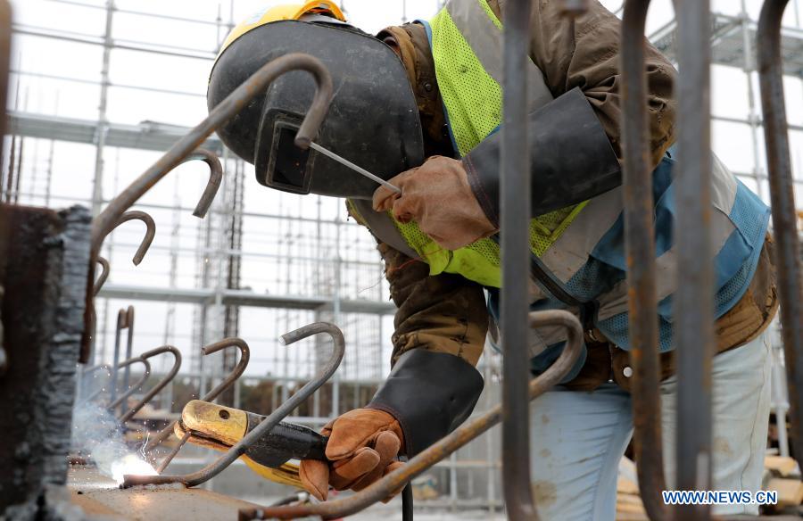 Zhang Xingfa operates a welding gun at a construction site in east China