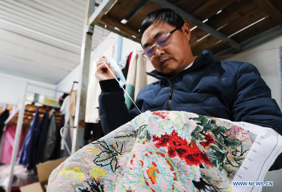 Zhang Xingfa works on a piece of cross-stitch in his temporary shed in east China