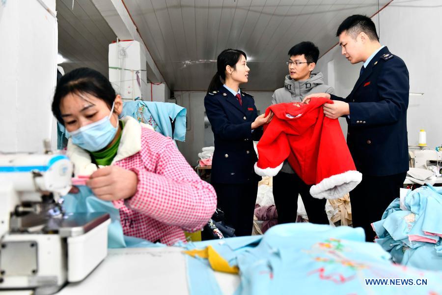 Staff members with local revenue department introduces tax preferential policies to Hu Chunqing (2nd R) at his workshop in Daji Township of Caoxian County, east China