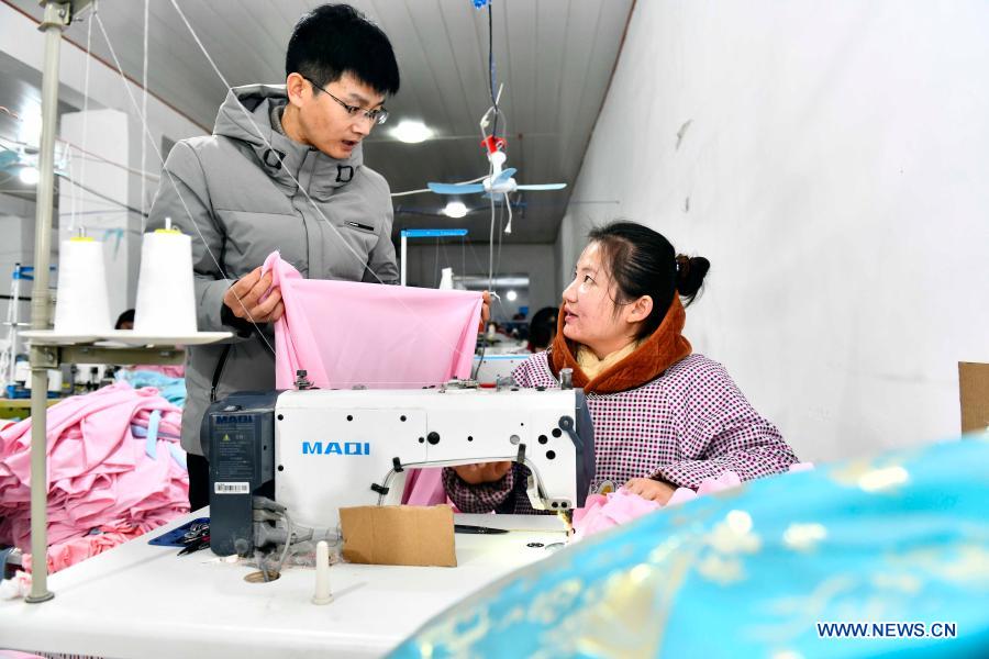 Hu Chunqing (L) communicates with a worker at his workshop in Daji Township of Caoxian County, east China