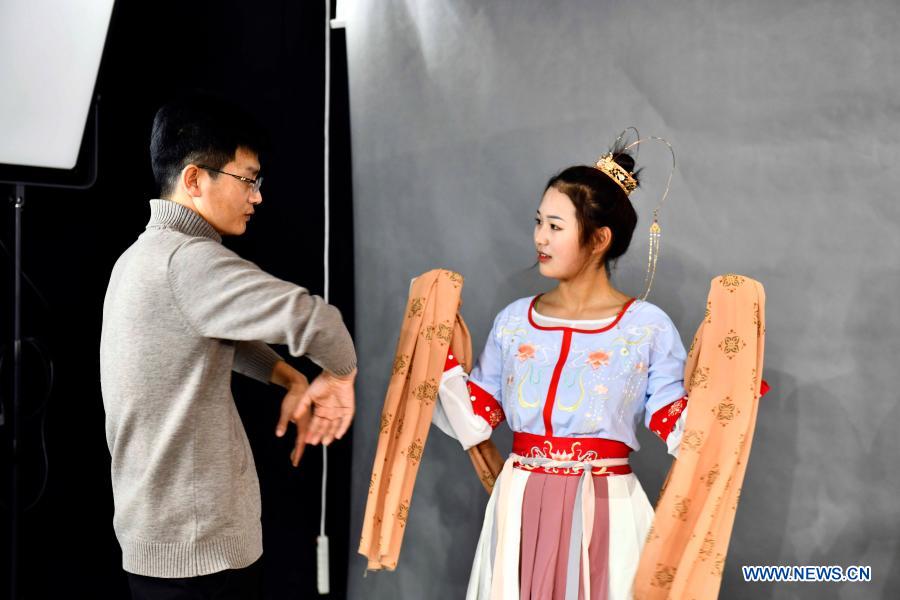 Hu Chunqing (L) communicates with a student at the studio of a secondary vocational school in Caoxian County, east China