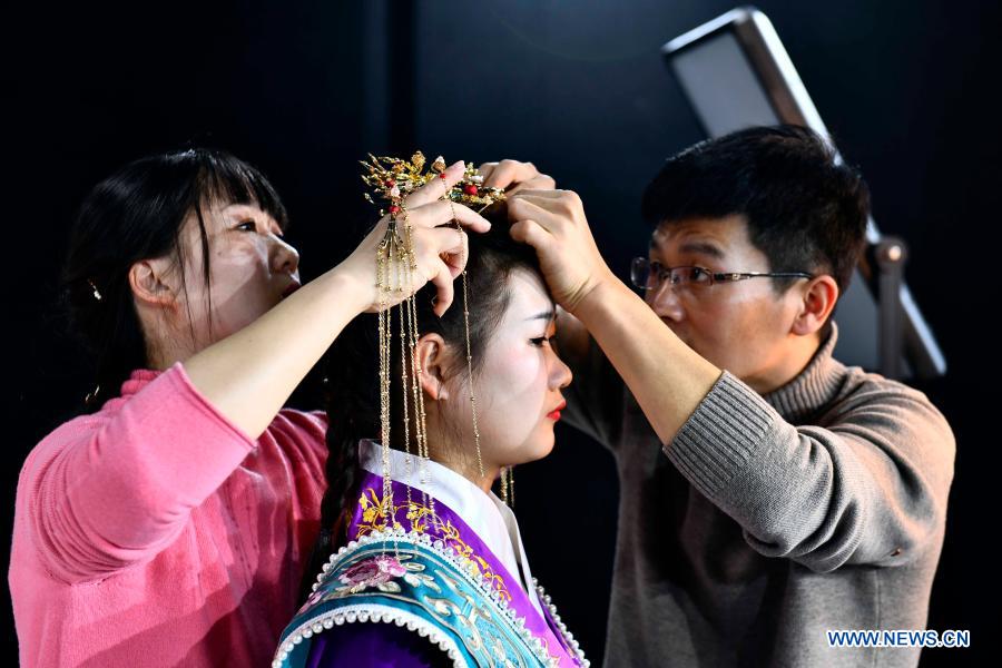 Hu Chunqing (R) and his wife Meng Xiaoxia help a student put on headgear at a secondary vocational school in Caoxian County, east China
