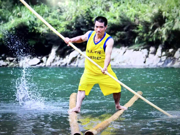 A wood surfer uses just one or two pieces of thin log and a bamboo pole to keep their balance. [Photo provided to chinadaily.com.cn]