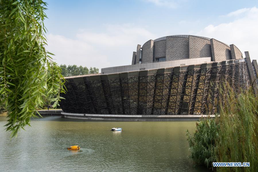 A cleaning boat (white) and a water quality monitoring boat (yellow) supported by 5G and autopilot technologies are in service beside the Wuzhen Grand Theater in Wuzhen, east China