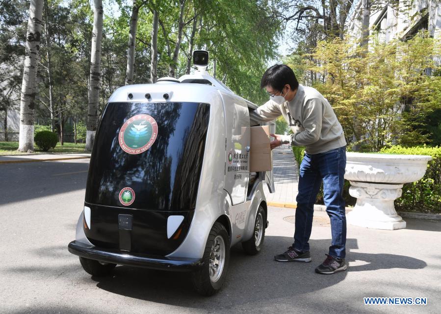 A member of staff takes goods from a 5G unmanned delivery car at the Beijing Institute of Technology in Beijing, capital of China, April 6, 2020. With the development of new technologies such as the 5G, artificial intelligence and BeiDou Navigation Satellite System (BDS), unmanned technology is injecting impetus into traditional industries as well as making people