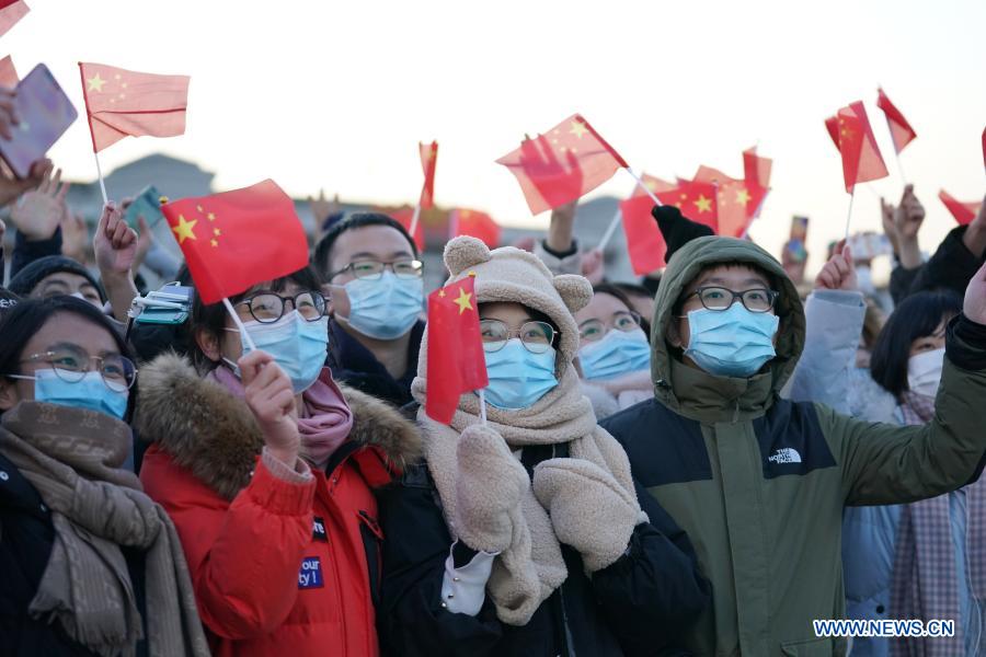 People wave Chinese national flags after a national flag-raising ceremony was held at the Tian