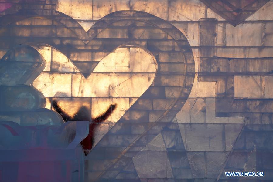 Sun Hongyan poses for a photo behind his work in the venue of Harbin Ice and Snow World in northeast China