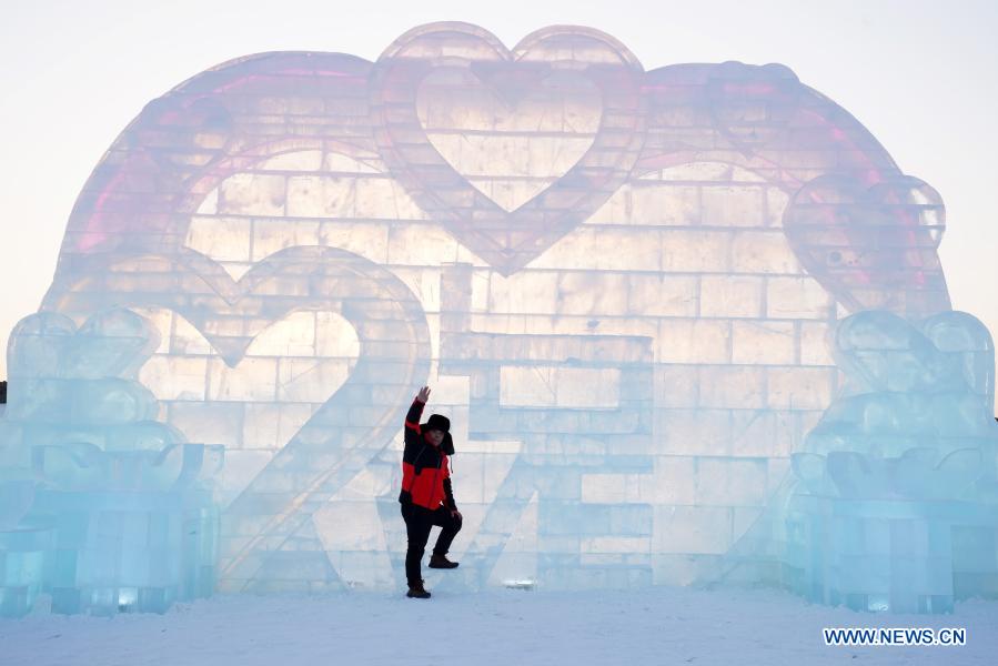 Sun Hongyan poses for a photo in front of his work in the venue of Harbin Ice and Snow World in northeast China