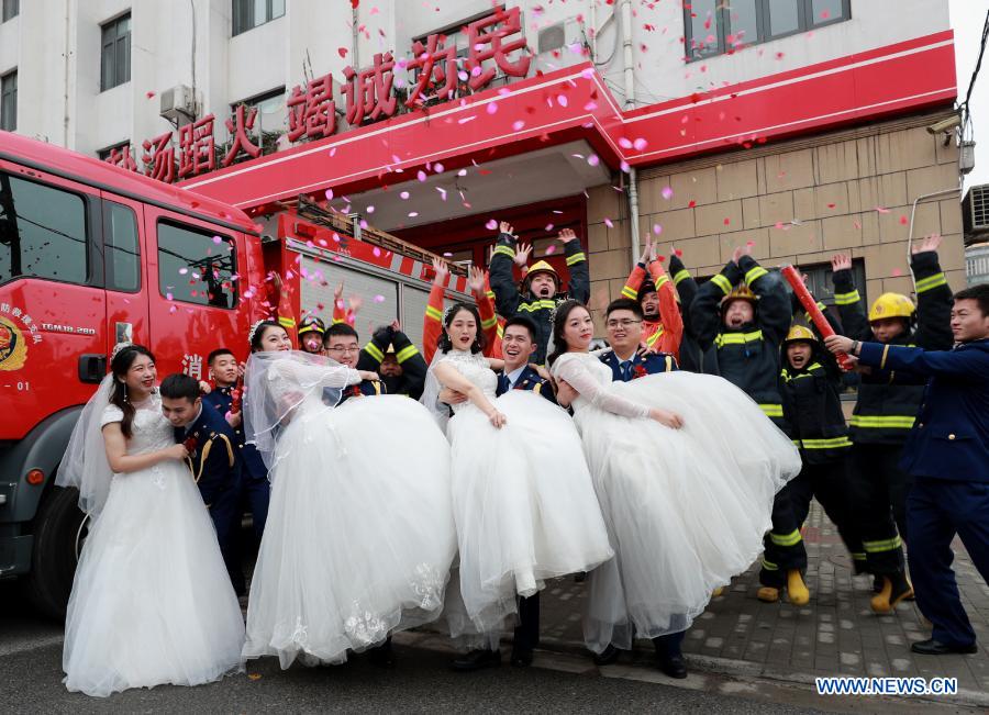 Firefighters and their wives pose for wedding photos during a group wedding ceremony in east China