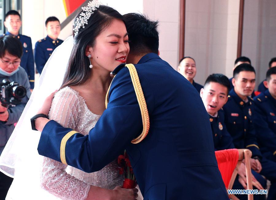 Firefighter Yuan Yang hugs his bride Xu Lu during a group wedding ceremony in east China