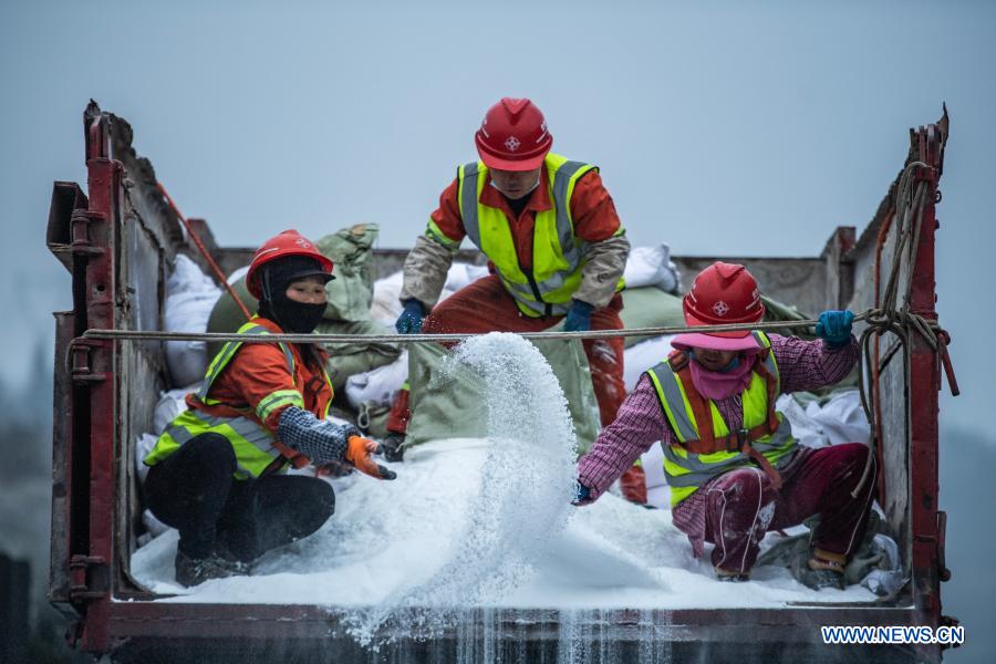 Workers sprinkle salt to clear ice off a road in southwest China