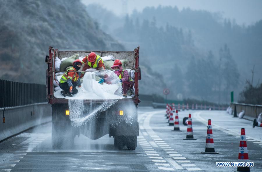 Workers sprinkle salt to clear ice off a road in southwest China