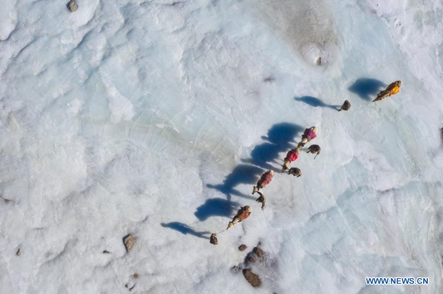 Aerial photo taken on Dec. 25, 2020 shows team members walking on a frozen river with yaks during a border patrol in northwest China