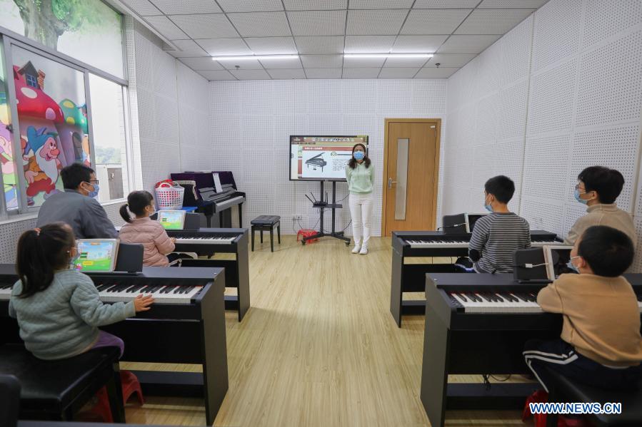Children accompanied by their parents take part in a free piano lesson at the youth activity center in Haikou, south China