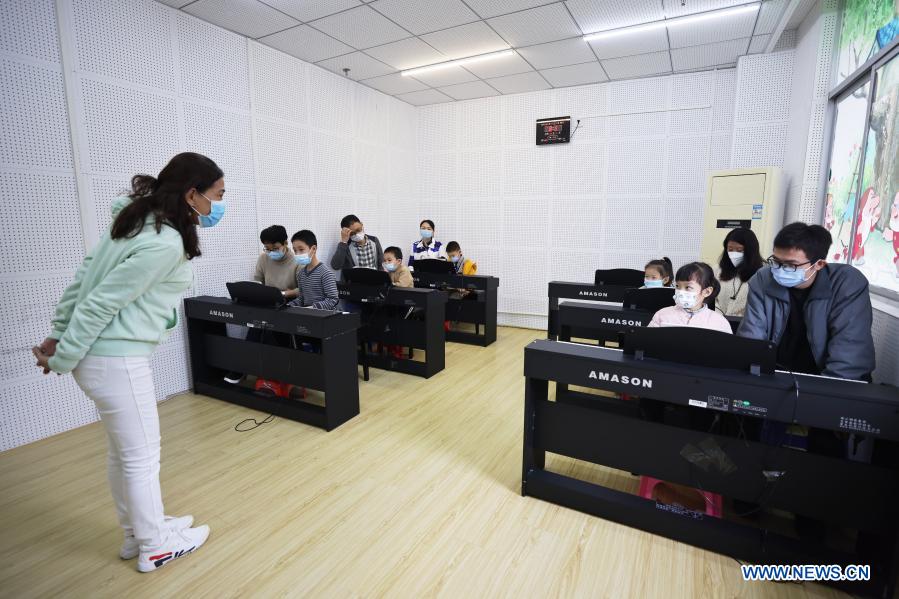 Children accompanied by their parents take part in a free piano lesson at the youth activity center in Haikou, south China