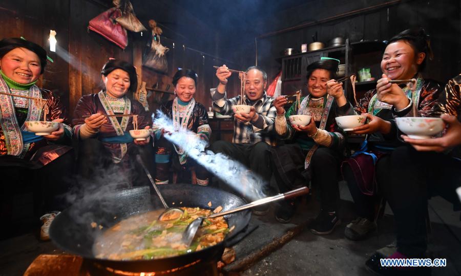 Lan Shengkui (3rd R) tastes noodles made with red sorghum flour at Wuying Village, which lies on the border between south China