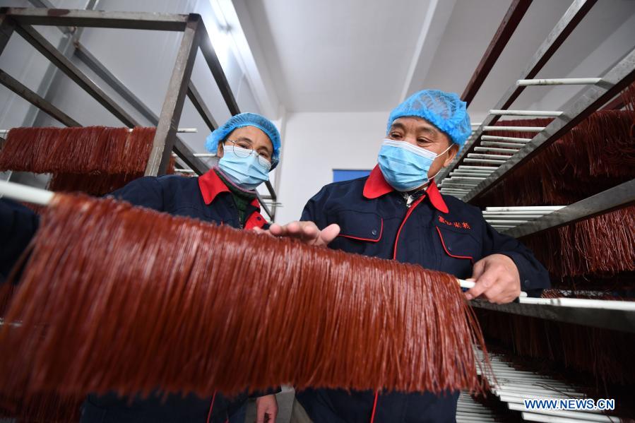 Lan Shengkui (R) checks noodles made with red sorghum flour at a noodles processing factory in Liuzhou, south China