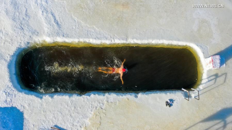 Photo taken with a drone on Jan. 22, 2021 shows Yan Xiangbin swimming in the icy water in Hulun Buir, north China