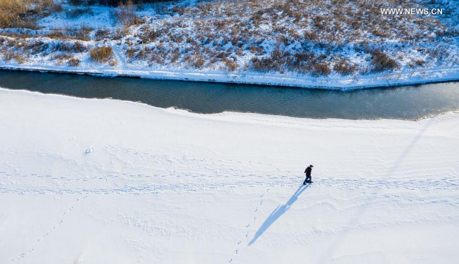Photo taken with a drone on Jan. 22, 2021 shows Yan Xiangbin walking on the frozen Yimin River in Hulun Buir, north China