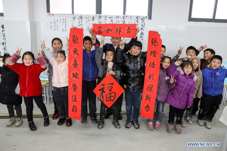 Yang Shaoshu (C, rear) takes part in a Spring Festival couplets writing activity at Jinxiu School in Qianxi County, Bijie, southwest China