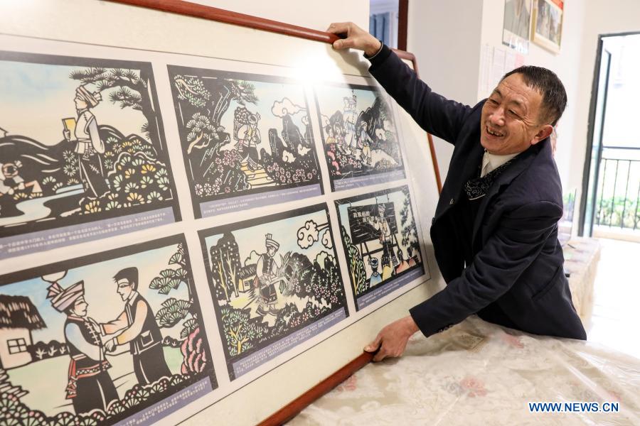 Yang Shaoshu illustrates his stories of leading students to school along the cliff path through paper-cut pictures in Qianxi County, Bijie, southwest China