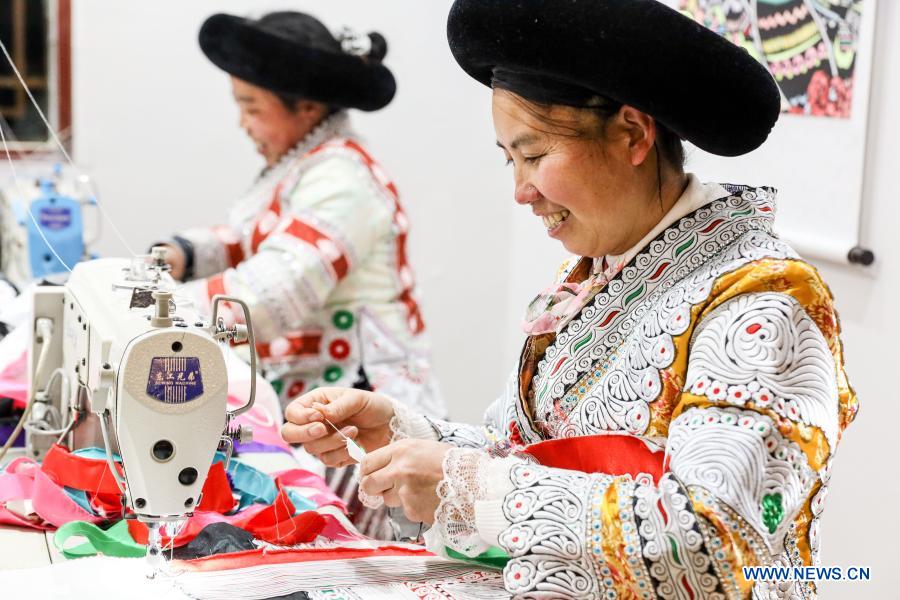 Villagers process garments at a poverty-alleviation workshop in Huawu Village, Xinren Miao Township, Qianxi County, Bijie City of southwest China