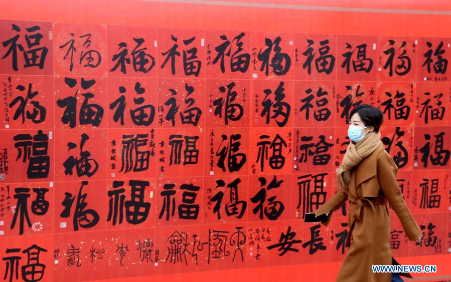 A woman walks past an exhibition poster of the Chinese character "Fu," meaning blessings, for the upcoming Chinese Lunar New Year in Changzhou City, east China